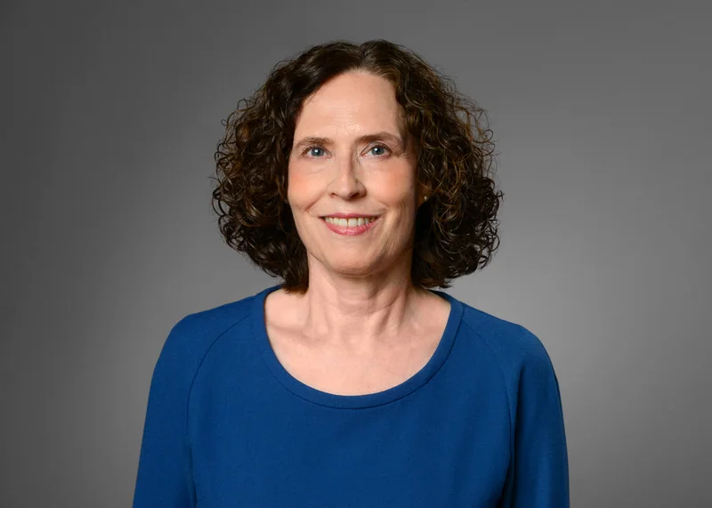 Frau mit dunklen Locken in einer blauen Bluse