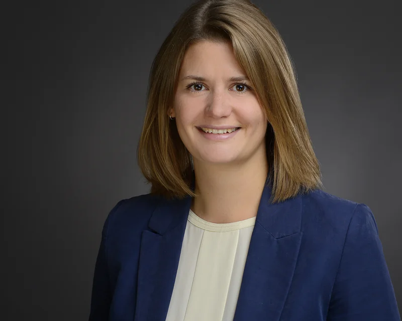 Bewerbungsportrait einer Frau im blauen Blazer vor grauem Hintergrund