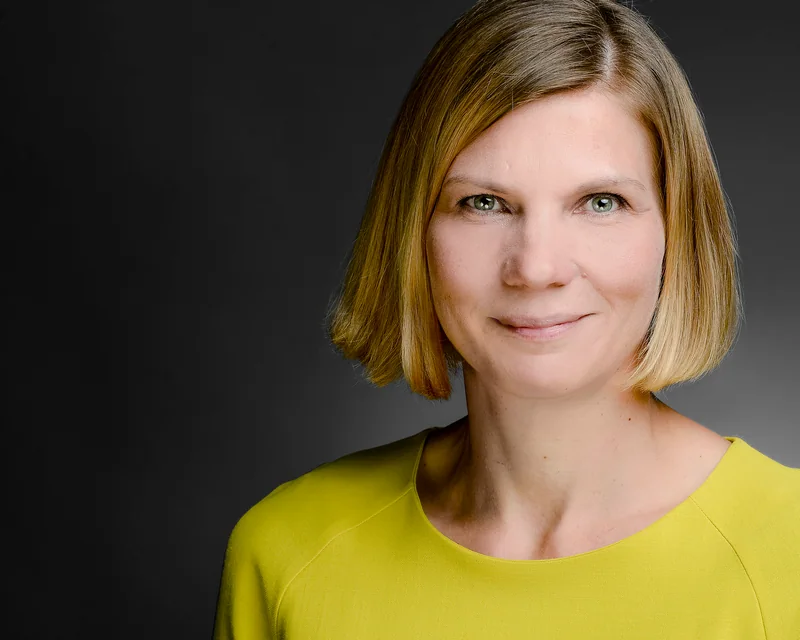 Frau mit kurzen hellen Haaren in gelbem Oberteil