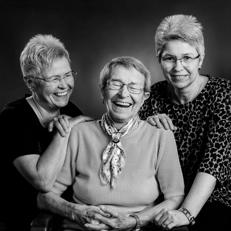Drei Frauen sitzen lachend nebeneinander
