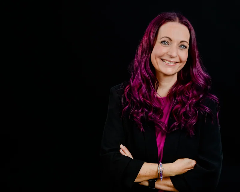 Frau mit violettem Haar vor schwarzem Hintergrund