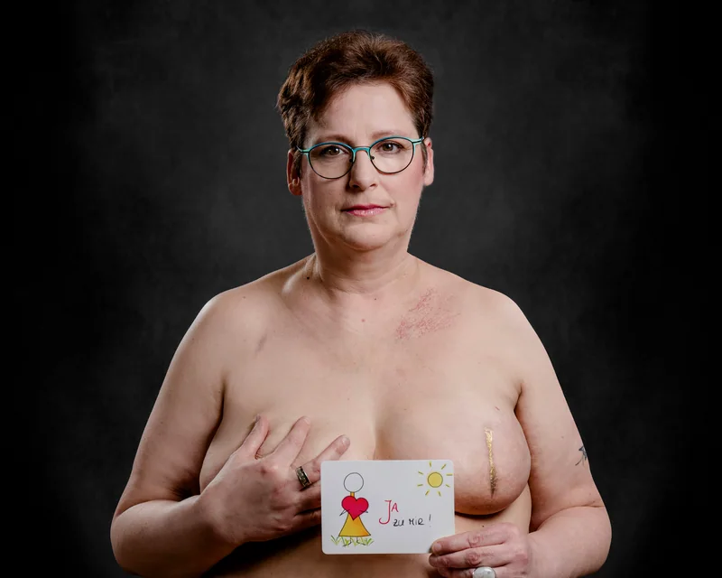 Portrait einer Frau mit Brille und einer kleinen Karte in den Händen