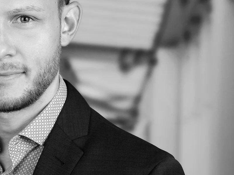 Angeschnittenes Portrait eines Mannes vor heller Architektur
