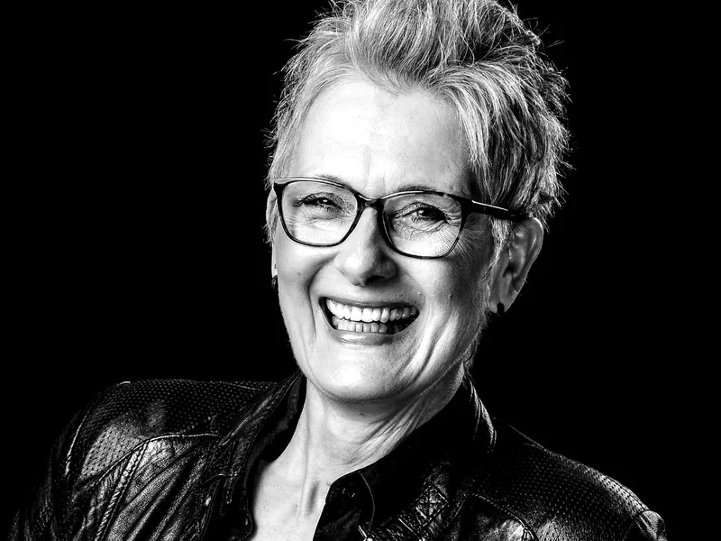 Lachende Frau mit Brille und Lederjacke
