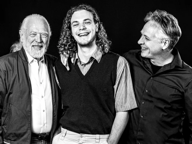 Drei Männer lachen einander im Gruppenportrait zu