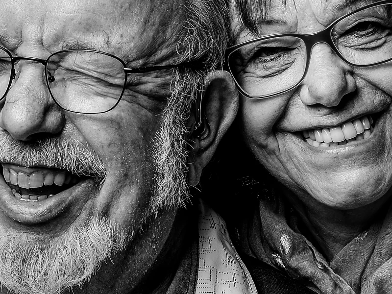 Nahaufnahme zweier lachender Personen mit Brille