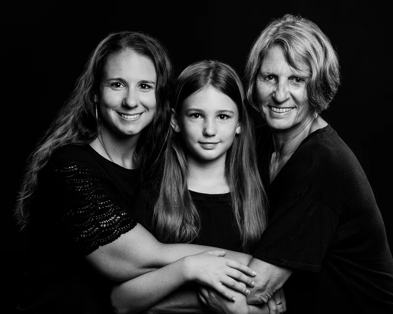 Drei Frauen stehen eng beieinander und lächeln