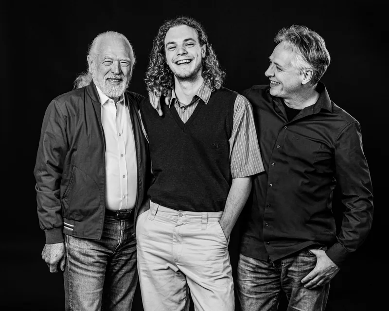 Drei Männer lachen einander im Gruppenportrait zu