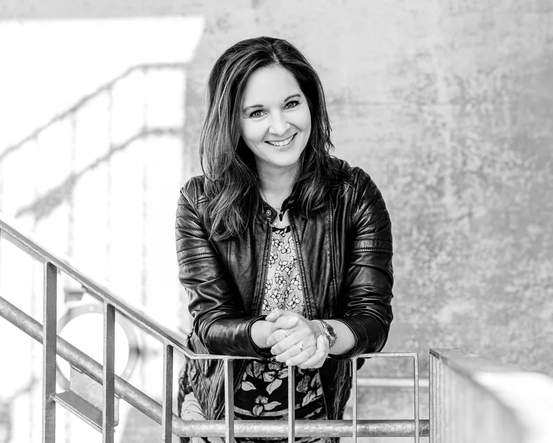 Anne Simon lehnt lächelnd an einem Treppengeländer